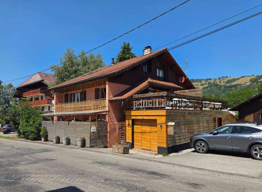 Discover this charming property featuring a multi-level home with a rustic wooden exterior and a welcoming balcony.
