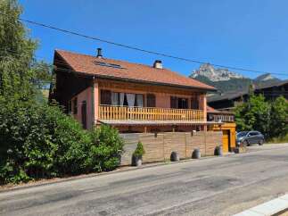 Charming alpine home featuring a spacious wooden balcony perfect for enjoying mountain views.