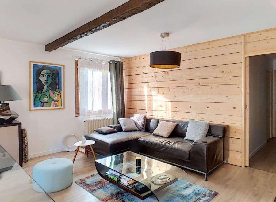 Experience cozy living in this charming room featuring a dark leather sectional sofa adorned with plush throw pillows.