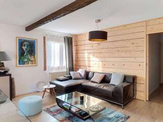Experience cozy living in this charming room featuring a dark leather sectional sofa adorned with plush throw pillows.