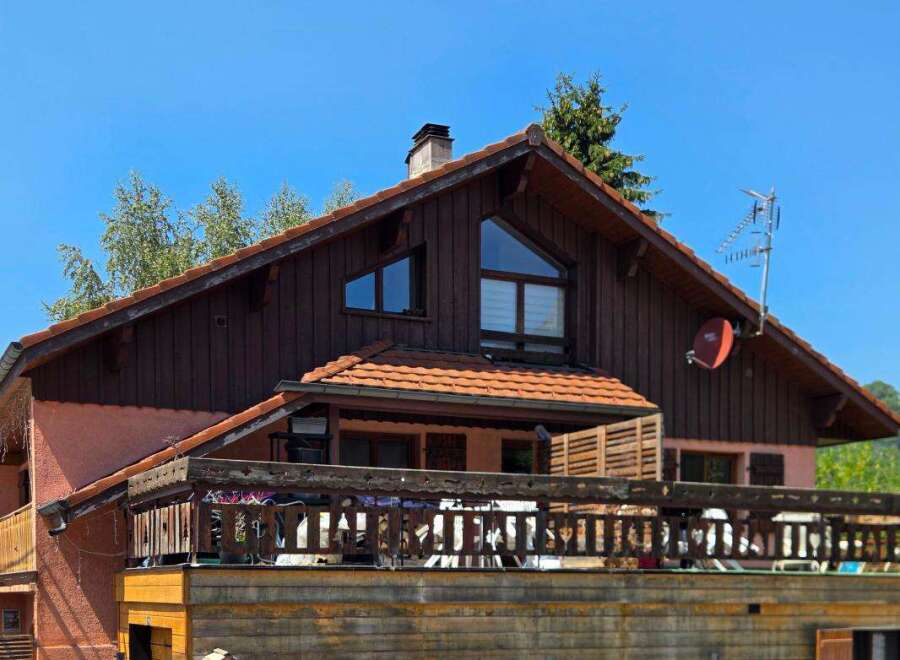 This charming property features a rustic wooden exterior complemented by a warm terracotta roof.