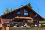 This charming property features a rustic wooden exterior complemented by a warm terracotta roof.