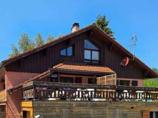 This charming property features a rustic wooden exterior complemented by a warm terracotta roof.