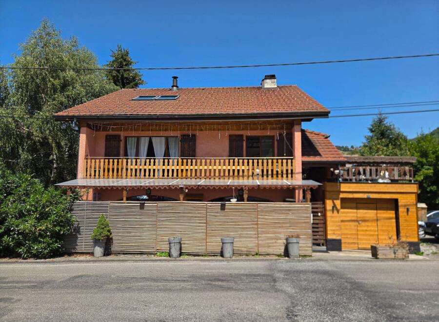 Charming two-story home featuring a spacious wooden balcony perfect for outdoor relaxation and entertaining.