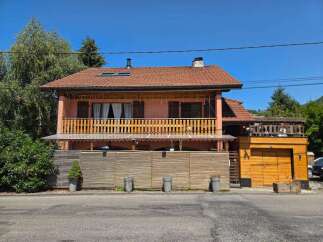 Charming two-story home featuring a spacious wooden balcony perfect for outdoor relaxation and entertaining.