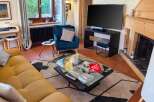 This cozy living room features a comfortable mustard-yellow sofa and a plush teal armchair, perfect for relaxing.