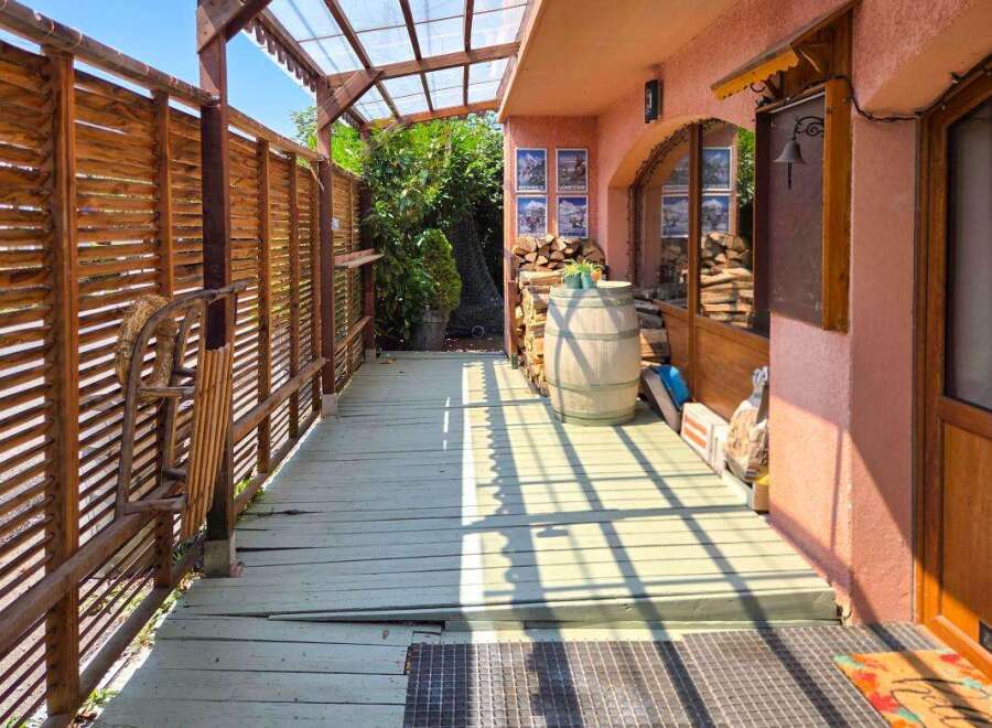 Discover this charming property featuring a rustic wooden porch with a slatted fence and a covered walkway, perfect for enjoying the outdoors.