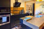 Discover this modern kitchen featuring sleek black cabinetry and a striking wood-paneled backsplash.