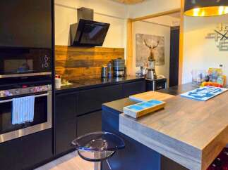 Discover this modern kitchen featuring sleek black cabinetry and a striking wood-paneled backsplash.