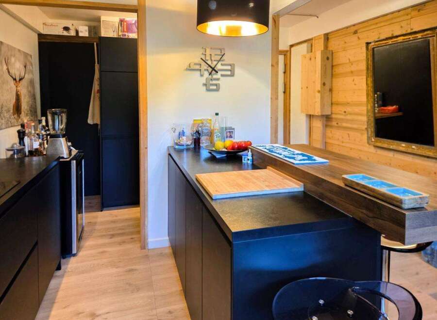 Discover this modern kitchen featuring sleek black cabinetry and a stunning wooden countertop island, perfect for meal preparation and casual dining.