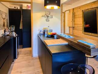 Discover this modern kitchen featuring sleek black cabinetry and a stunning wooden countertop island, perfect for meal preparation and casual dining.