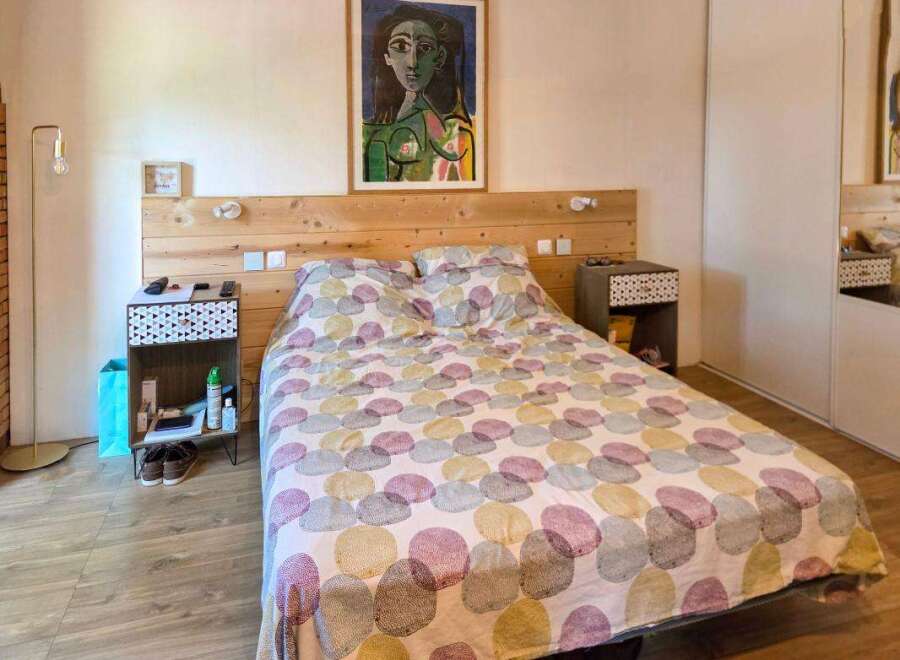 Discover this charming bedroom featuring a comfortable bed with a unique patterned duvet and a rustic wooden headboard.