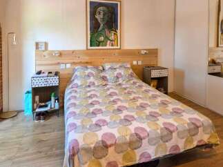 Discover this charming bedroom featuring a comfortable bed with a unique patterned duvet and a rustic wooden headboard.