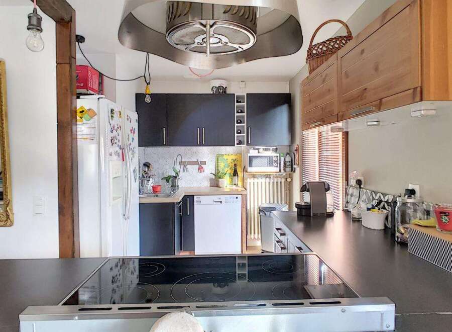 Discover this charming kitchen featuring sleek dark cabinetry and a modern stainless steel range hood.