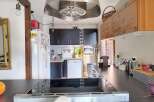 Discover this charming kitchen featuring sleek dark cabinetry and a modern stainless steel range hood.