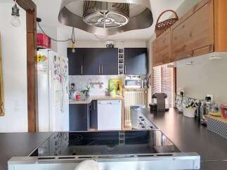 Discover this charming kitchen featuring sleek dark cabinetry and a modern stainless steel range hood.