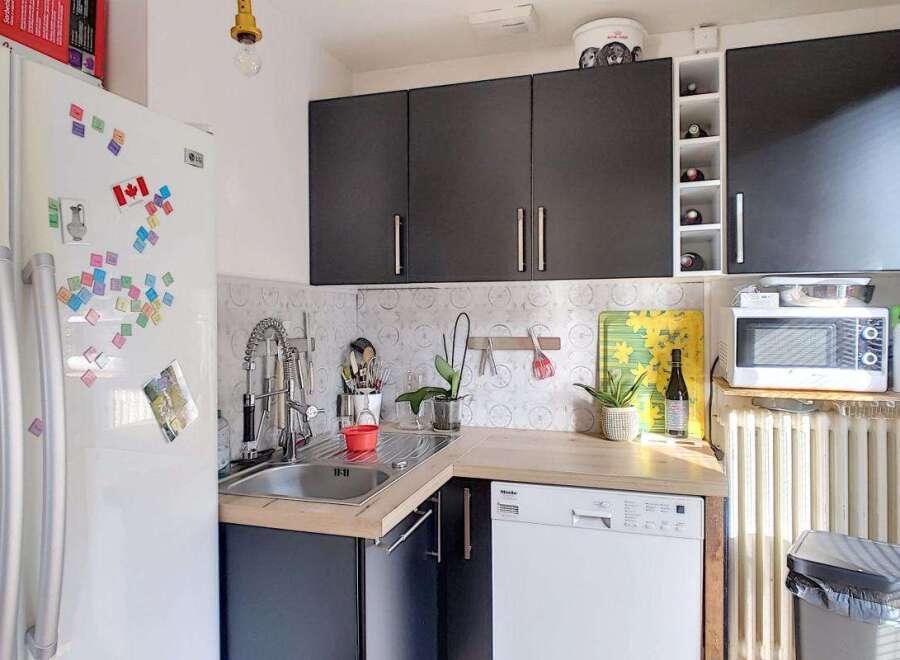 Discover this charming kitchen featuring a sleek black cabinetry set above a spacious countertop and sink area.