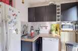 Discover this charming kitchen featuring a sleek black cabinetry set above a spacious countertop and sink area.