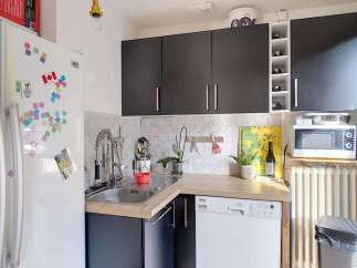 Discover this charming kitchen featuring a sleek black cabinetry set above a spacious countertop and sink area.