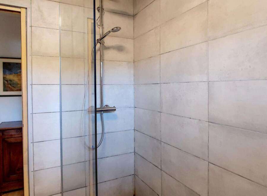Step into a refreshing shower experience with this modern bathroom featuring a sleek chrome showerhead and controls.