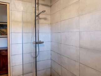 Step into a refreshing shower experience with this modern bathroom featuring a sleek chrome showerhead and controls.