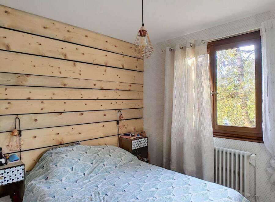 Experience rustic charm in this cozy bedroom featuring a unique wood-paneled accent wall and a stylish geometric-patterned duvet.