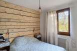 Experience rustic charm in this cozy bedroom featuring a unique wood-paneled accent wall and a stylish geometric-patterned duvet.