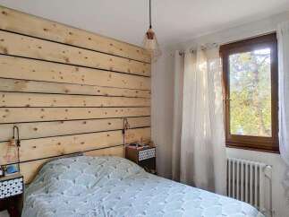 Experience rustic charm in this cozy bedroom featuring a unique wood-paneled accent wall and a stylish geometric-patterned duvet.