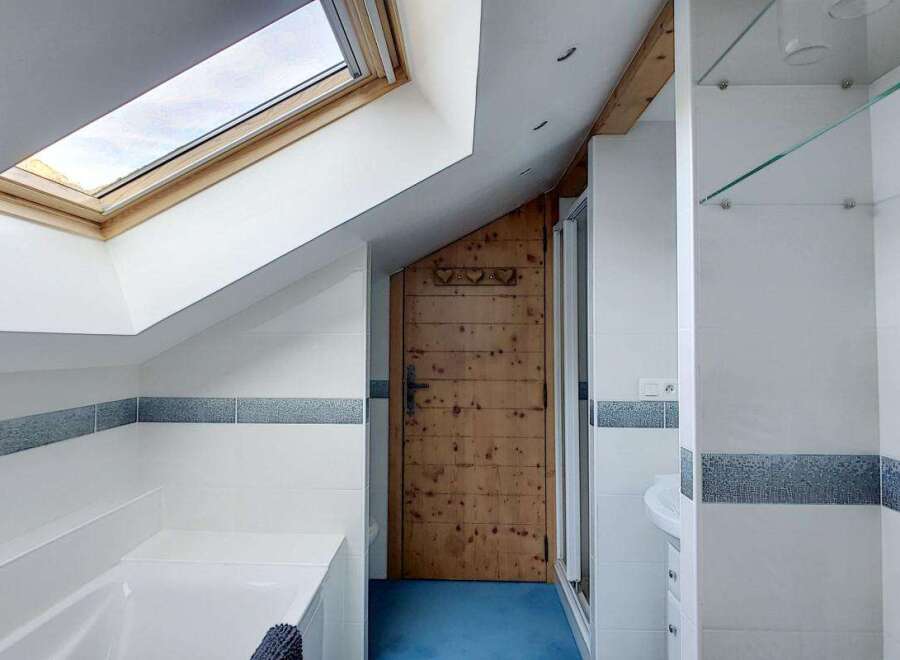 Experience a unique bathroom design featuring a charming wooden door and a skylight that floods the space with natural light.