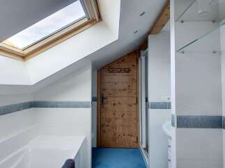 Experience a unique bathroom design featuring a charming wooden door and a skylight that floods the space with natural light.