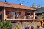 Charming alpine home featuring a beautiful balcony adorned with vibrant flowers, perfect for enjoying mountain views.