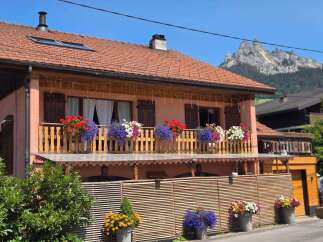 Charming alpine home featuring a beautiful balcony adorned with vibrant flowers, perfect for enjoying mountain views.