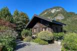 Nestled amidst lush greenery and towering mountains, this charming wooden cabin offers a serene retreat.
