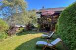 Enjoy a serene mountain getaway in this charming wooden chalet, complete with a spacious deck and lush green lawn perfect for relaxation.