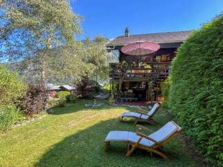 Enjoy a serene mountain getaway in this charming wooden chalet, complete with a spacious deck and lush green lawn perfect for relaxation.