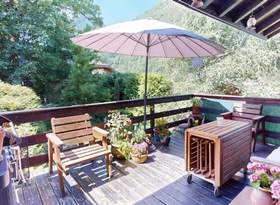 Enjoy outdoor living on this charming wooden deck, complete with comfortable seating and a large umbrella for shade.