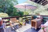 Enjoy outdoor living on this charming wooden deck, complete with comfortable seating and a large umbrella for shade.