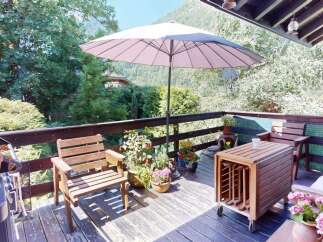 Enjoy outdoor living on this charming wooden deck, complete with comfortable seating and a large umbrella for shade.