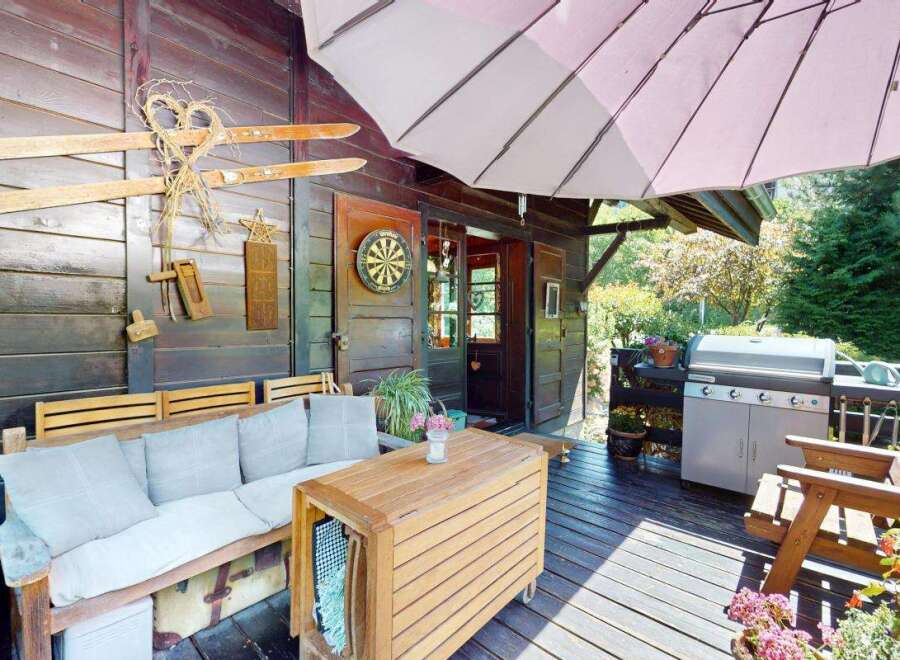 Enjoy outdoor living on this charming wooden deck, complete with a comfortable seating area and a built-in grill perfect for summer barbecues.