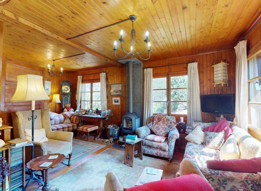 Experience rustic charm in this cozy living room, featuring warm wood paneling throughout and a traditional fireplace as the focal point.