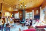 Experience rustic charm in this cozy living room, featuring warm wood paneling throughout and a traditional fireplace as the focal point.