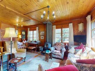 Experience rustic charm in this cozy living room, featuring warm wood paneling throughout and a traditional fireplace as the focal point.