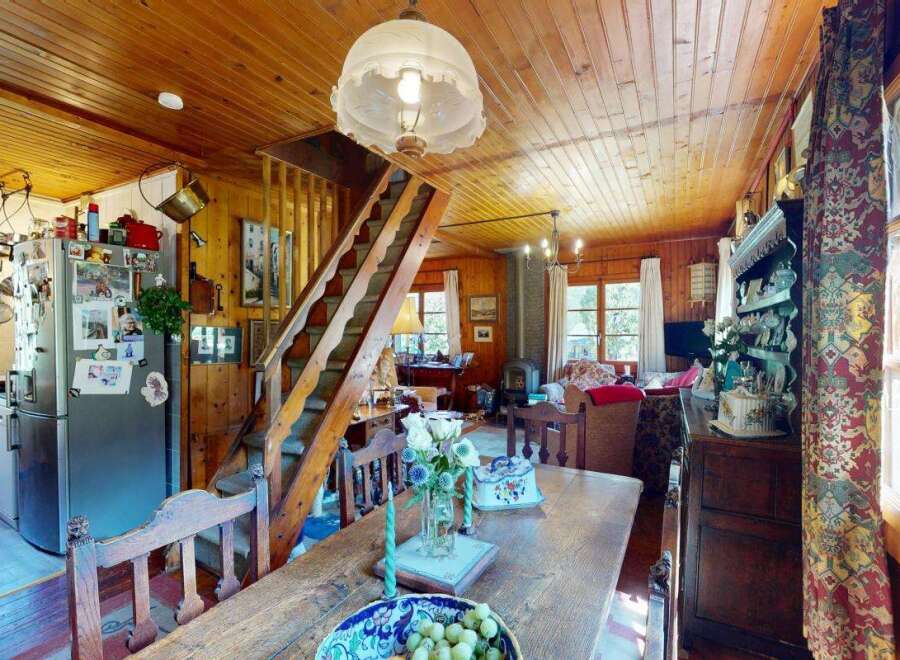 Step into this charming rustic home featuring a cozy living area with a wood-burning stove and a dining space perfect for family gatherings.
