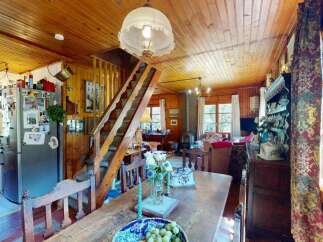 Step into this charming rustic home featuring a cozy living area with a wood-burning stove and a dining space perfect for family gatherings.
