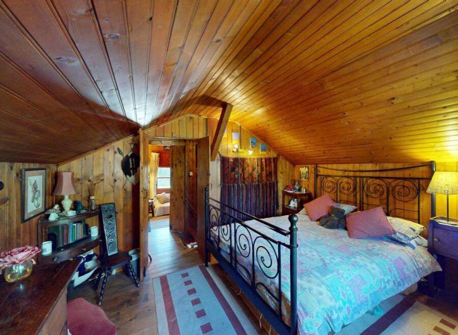 Experience rustic charm in this cozy bedroom featuring a beautifully paneled wood ceiling and walls.
