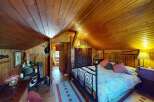 Experience rustic charm in this cozy bedroom featuring a beautifully paneled wood ceiling and walls.