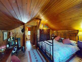 Experience rustic charm in this cozy bedroom featuring a beautifully paneled wood ceiling and walls.