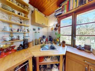 Charming rustic kitchen featuring open shelving stocked with glassware and pottery, a vintage red scale, and a large farmhouse sink.