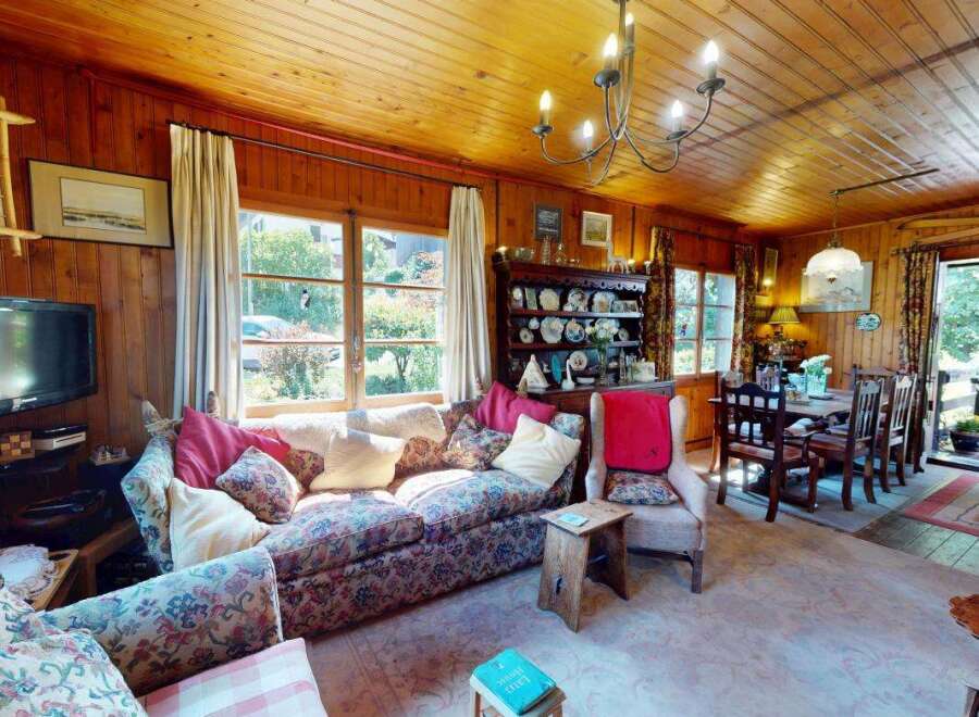 Step into this charming living and dining area, featuring warm wood paneling and a cozy floral sofa perfect for relaxation.