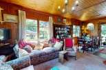 Step into this charming living and dining area, featuring warm wood paneling and a cozy floral sofa perfect for relaxation.